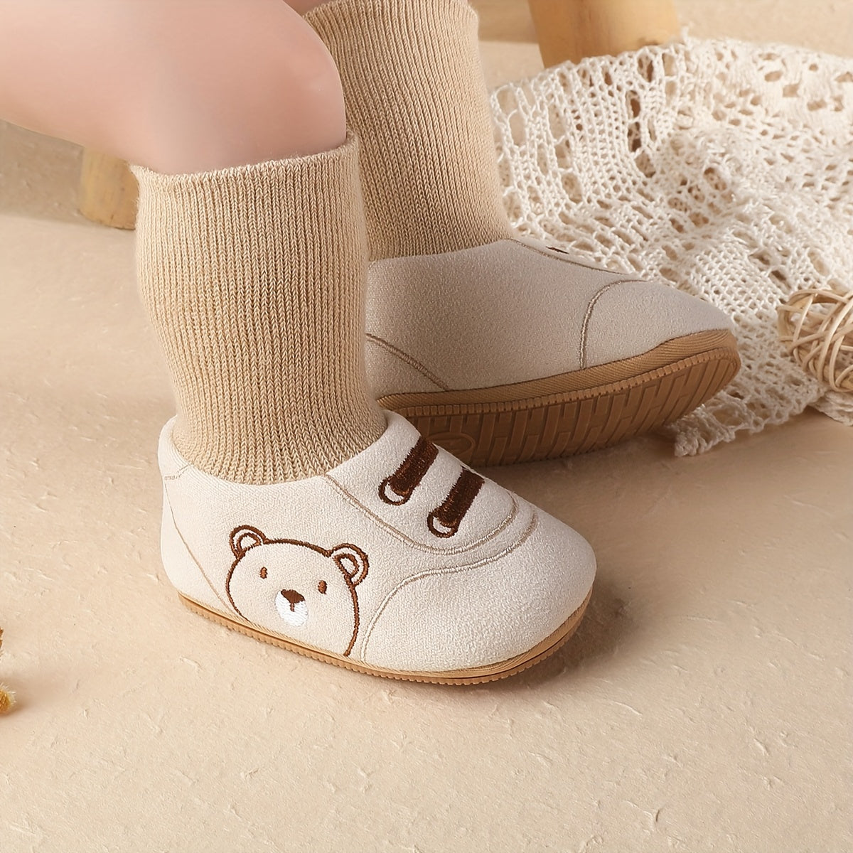 Beige baby sock booties with bear face, ribbed cuffs, and non-slip outsole