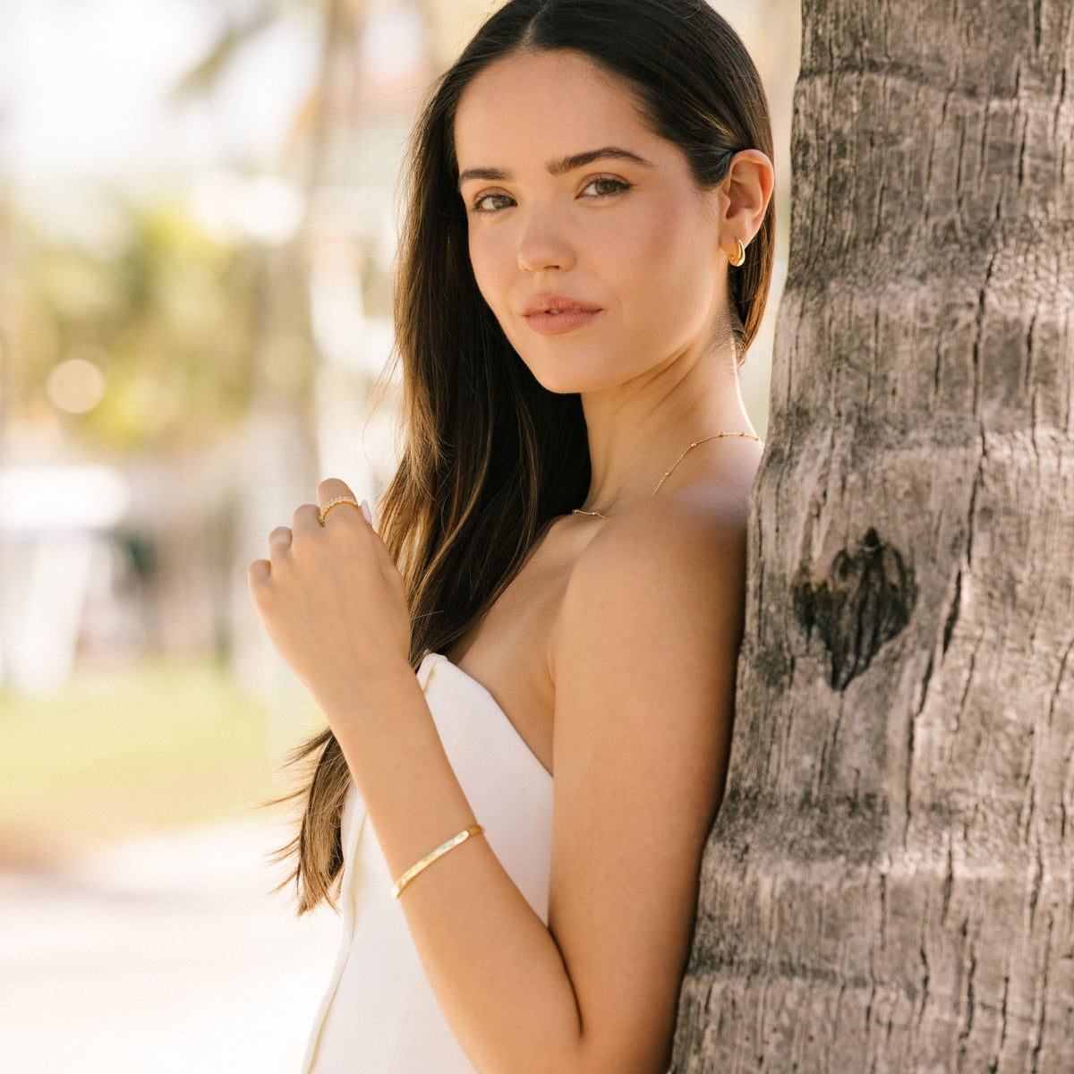 Gold-tone cuff bracelet worn with a stacked bracelet look.