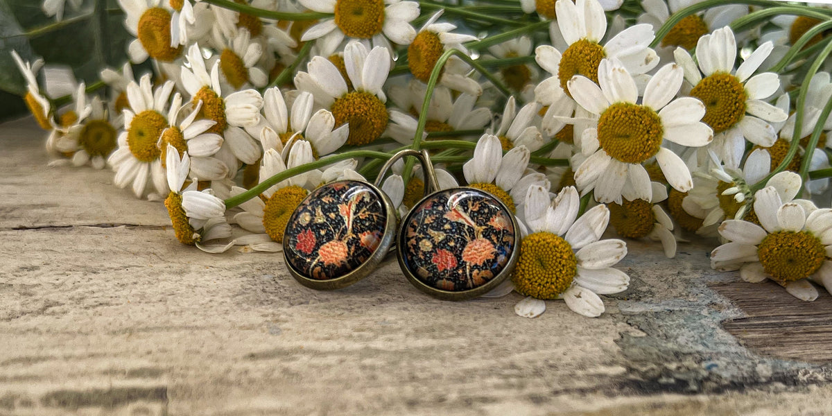 Pair of round floral stud earrings with orange blossoms and blue detailing, bronze finish.