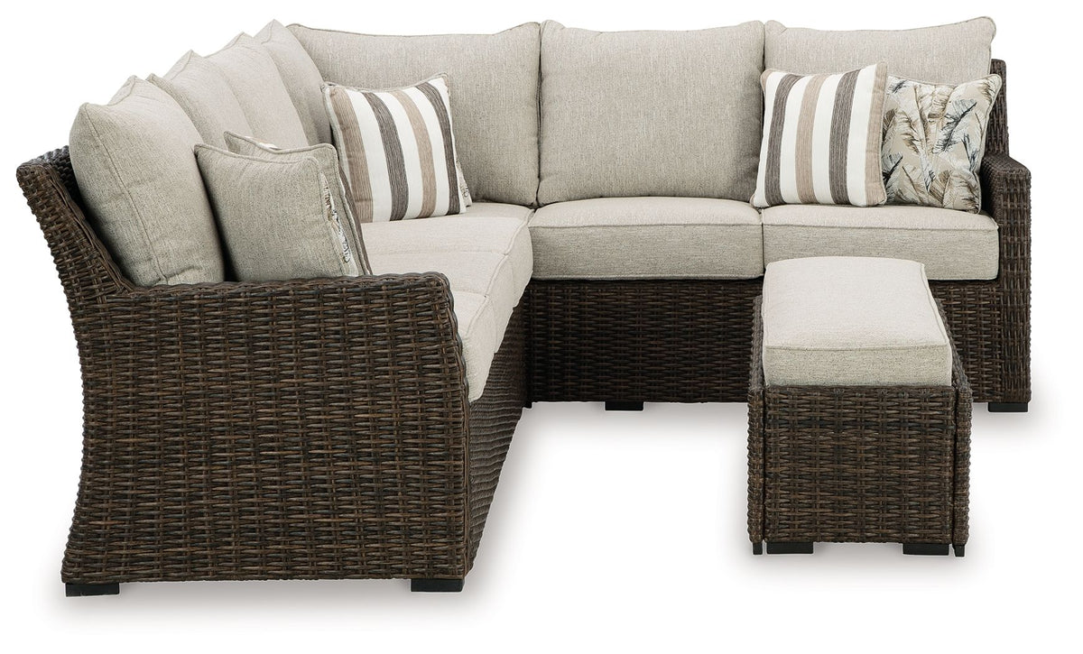 L-shaped sectional sofa with brown wicker base, light beige cushions and bench ottoman