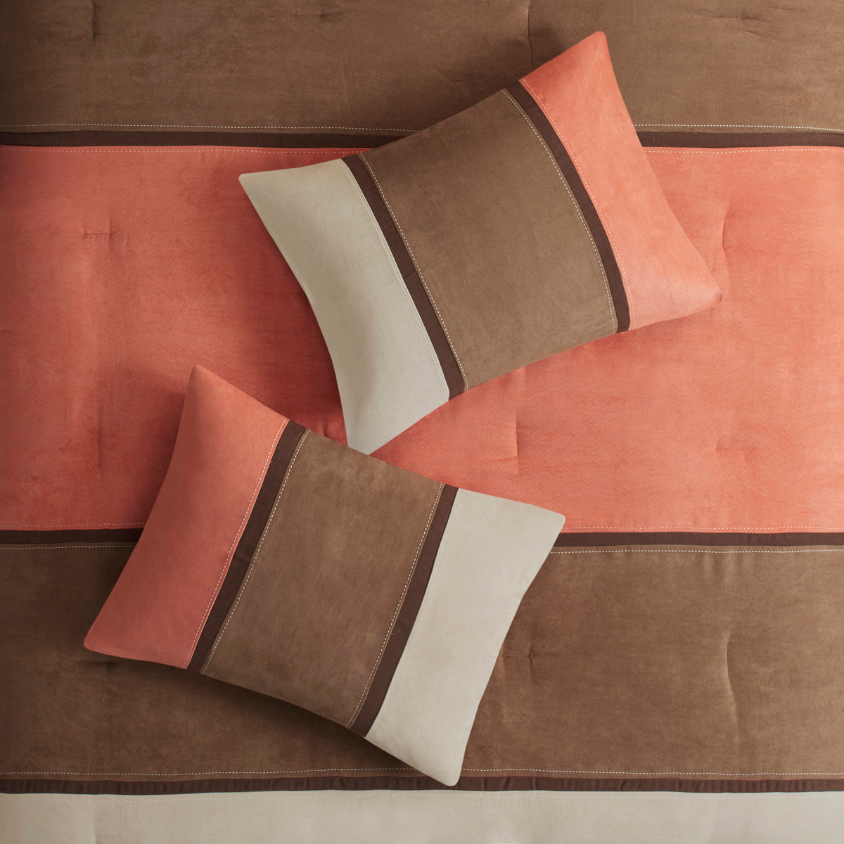 Decorative faux suede pillows in coral, brown, and cream with striped bands