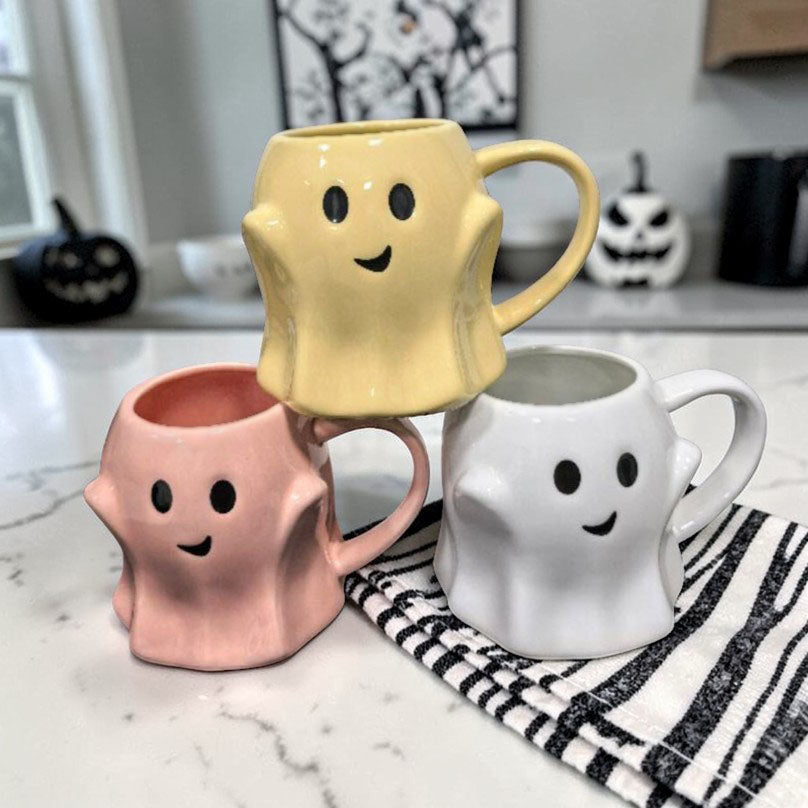Set of three ghost-shaped ceramic mugs in yellow, pink, and white with handles