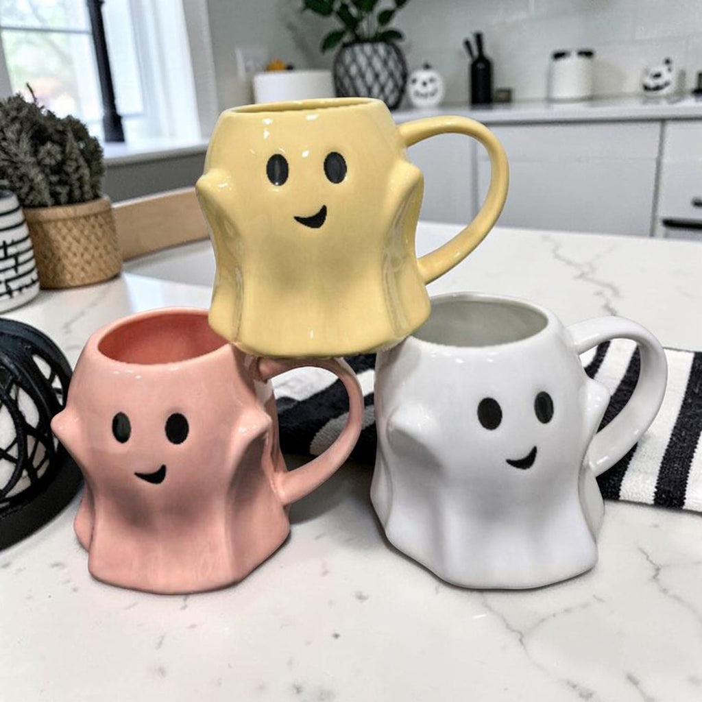 Stack of ghost-shaped mugs in yellow, pink, and white with smiling faces