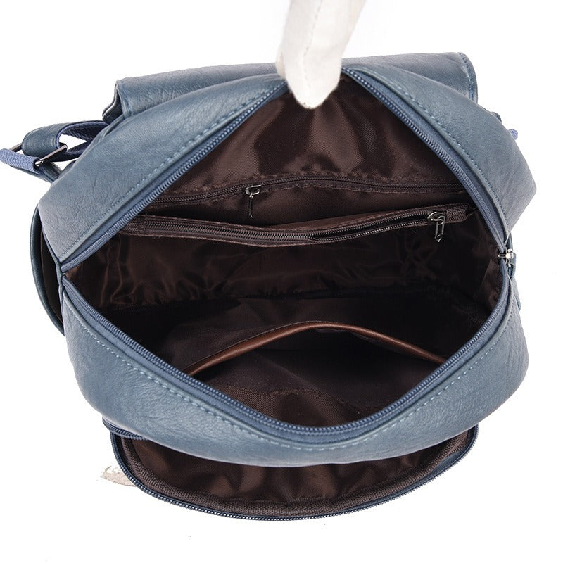 Light blue faux-leather backpack with top zipper and open interior pocket