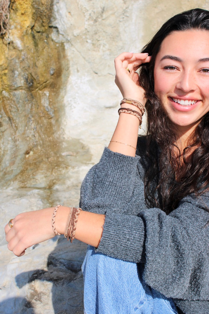 Braided brown hair tie bracelet set on wrist with gold coin charms and bead accents
