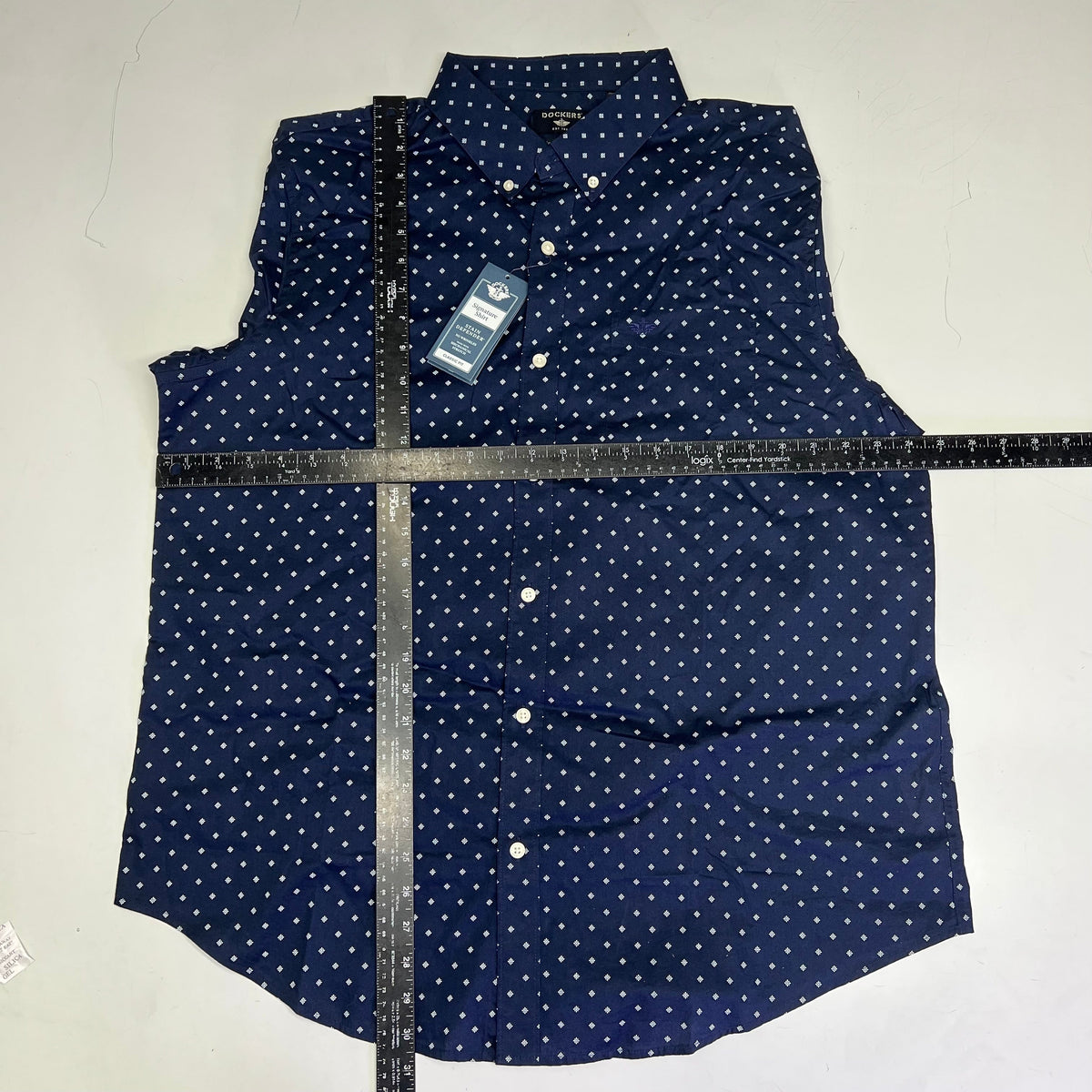 Men's navy button-up shirt front with white daisy pattern and hanging product tags.
