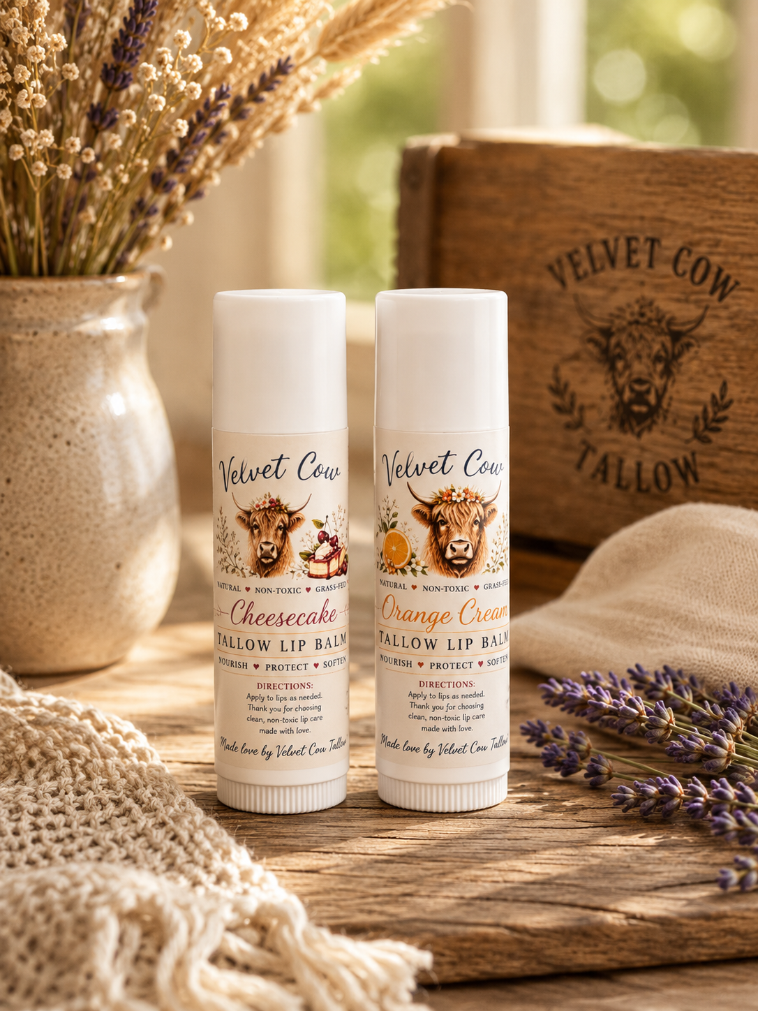 Two lip balm tubes on a wooden surface with lavender beside them