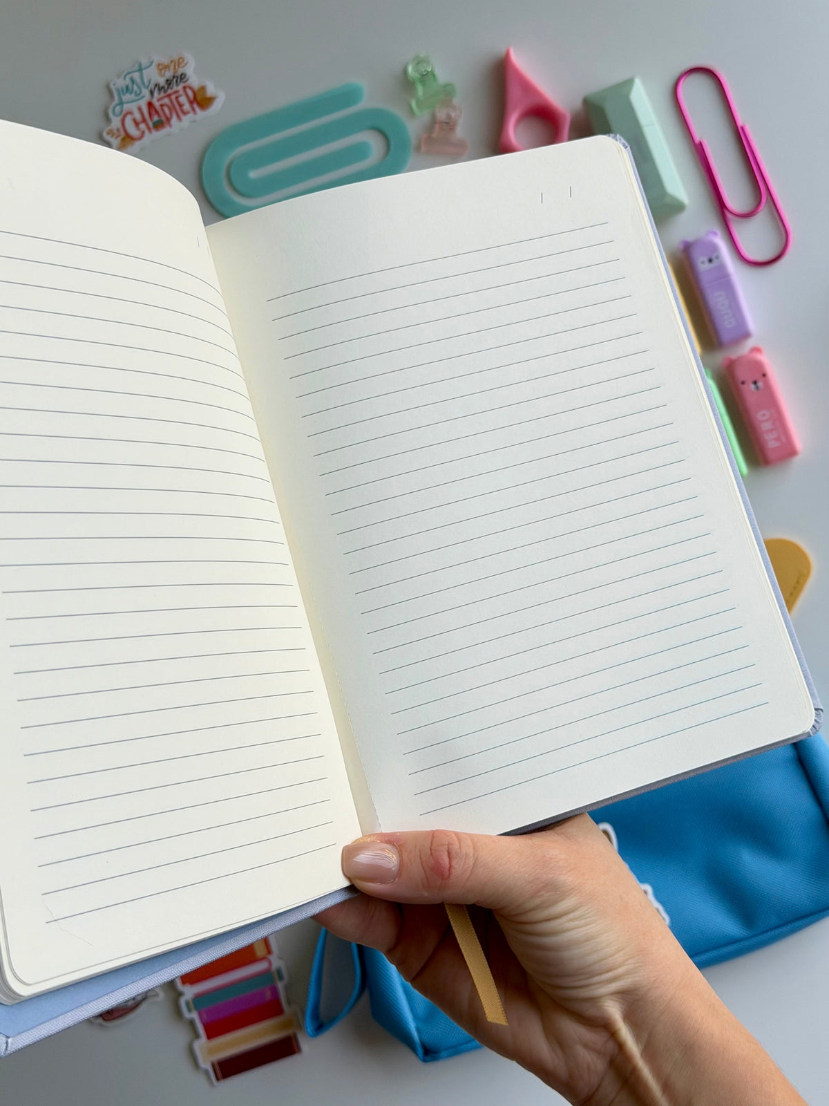 Cat-themed notebook with blank lined pages, held open in hand
