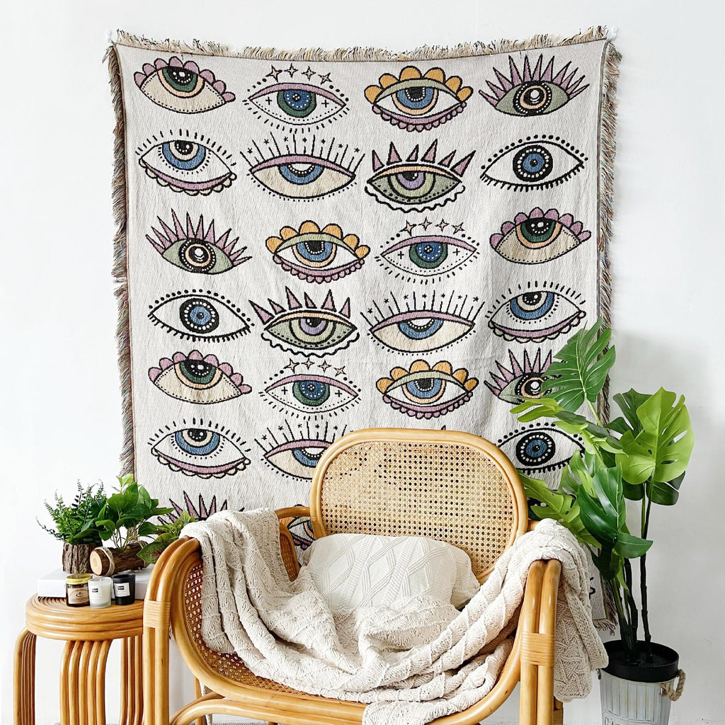 Evil eye blanket with all-over eye pattern, green accents, and fringed edge