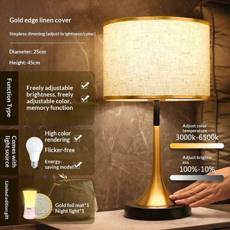 Gold table lamp with off-white fabric shade and gold base with dark round foot