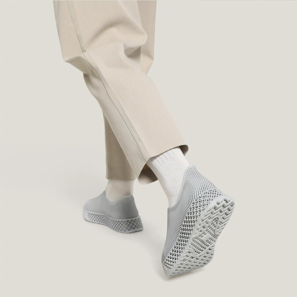 Close-up of light gray 3D-printed slip-on sneakers with knit texture and sole