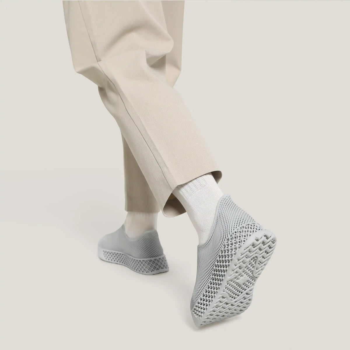 Close-up of light gray 3D-printed slip-on sneakers with knit texture and sole