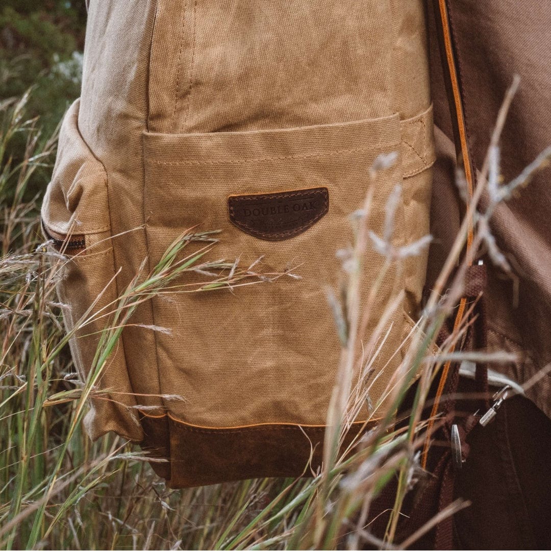Sand waxed canvas backpack with leather patch and front pocket, close-up view