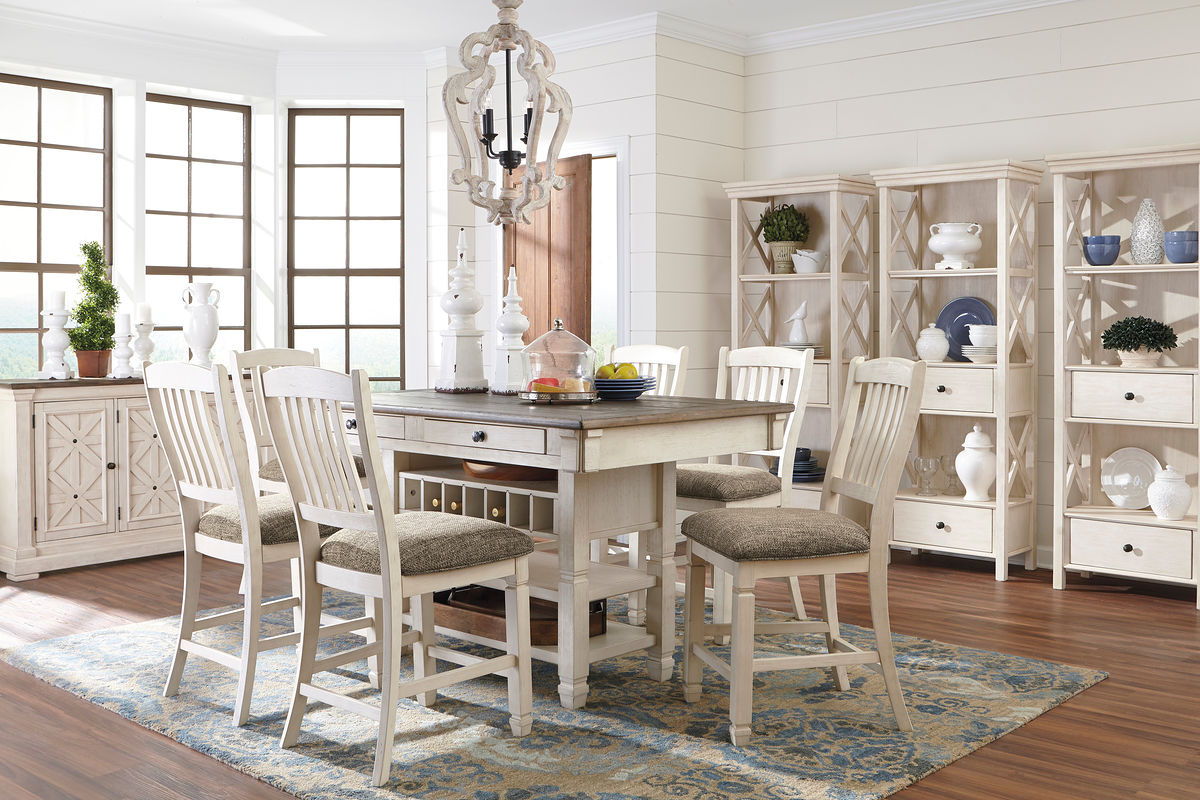 Beige rectangular counter table with gray upholstered chairs and display cabinet side storage.