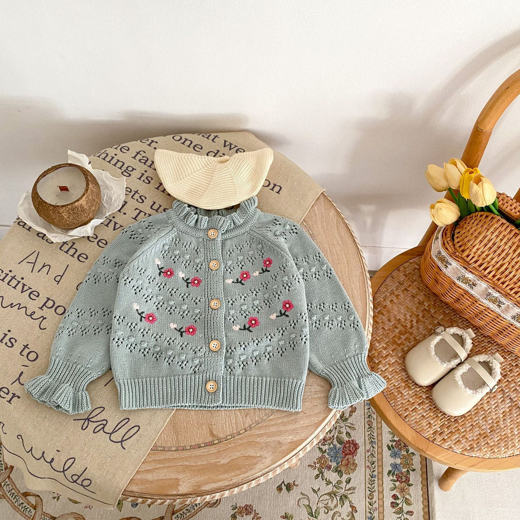 Blue-gray knit cardigan with rounded collar, button placket, and red flower embroidery.