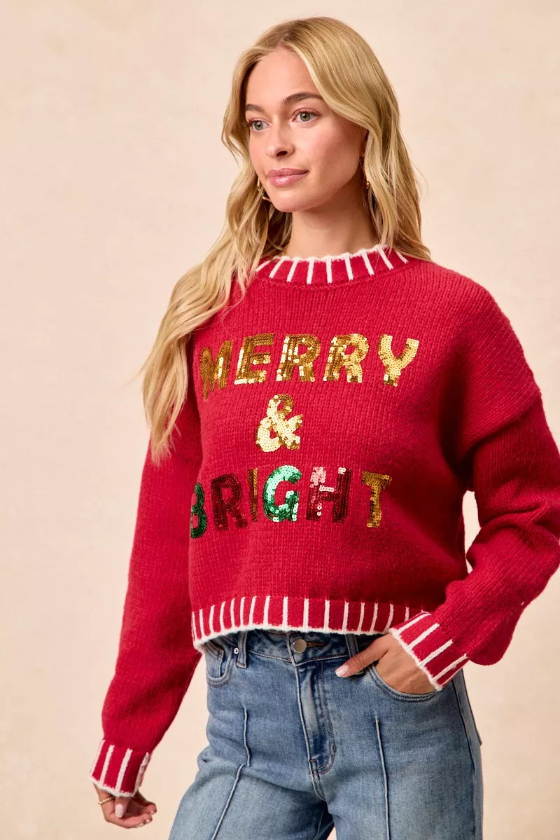Red sequin holiday sweater with “MERRY & BRIGHT” graphic and striped knit trim detail