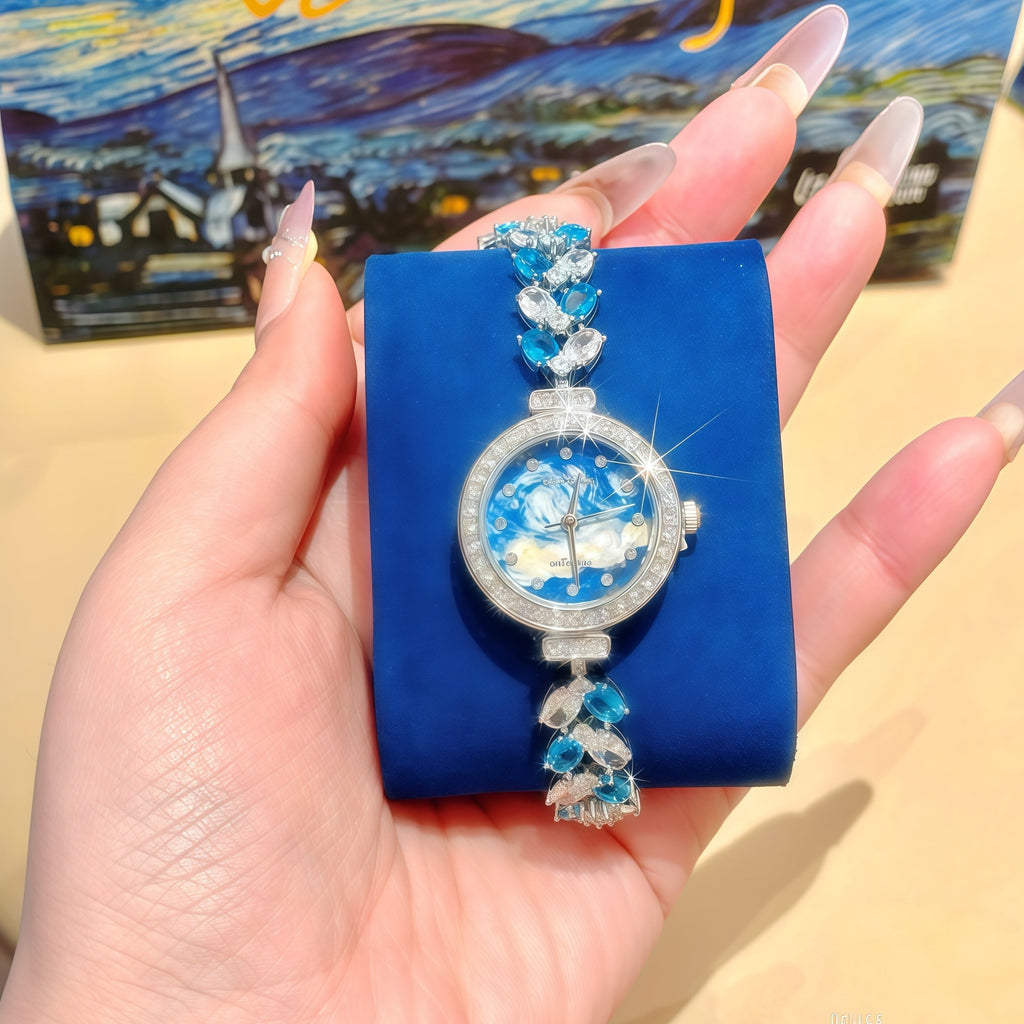 Blue floral dial wristwatch on display box, silver case with crystal-studded bracelet