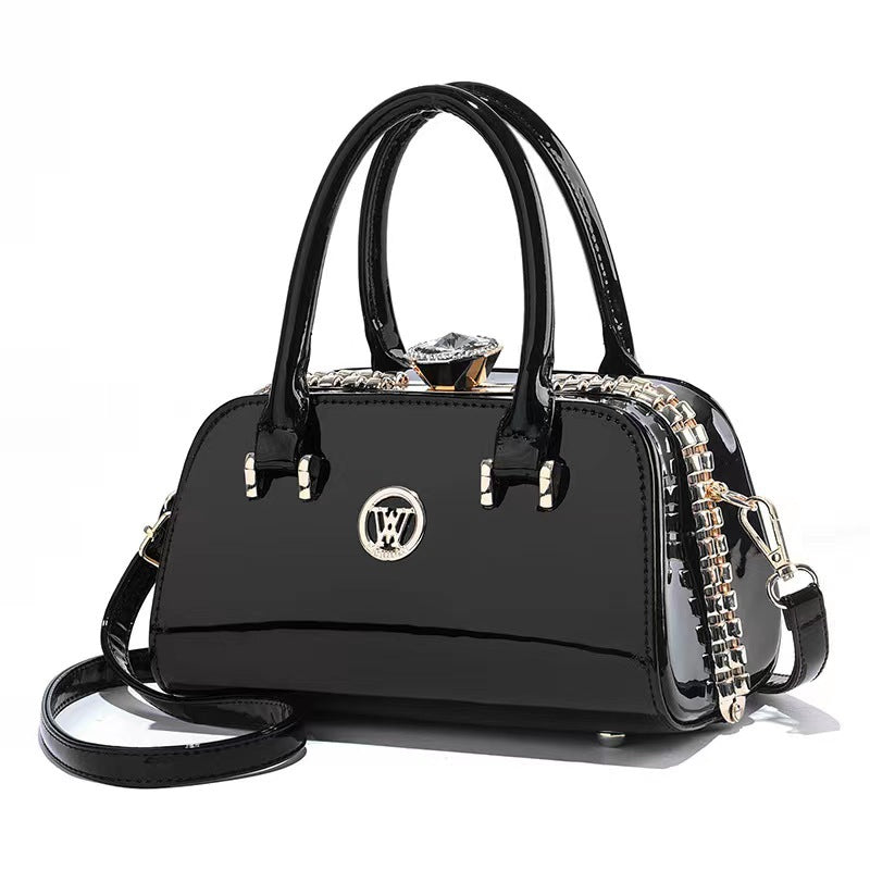 Black glossy patent leather handbag with top handles, chain strap, and logo emblem