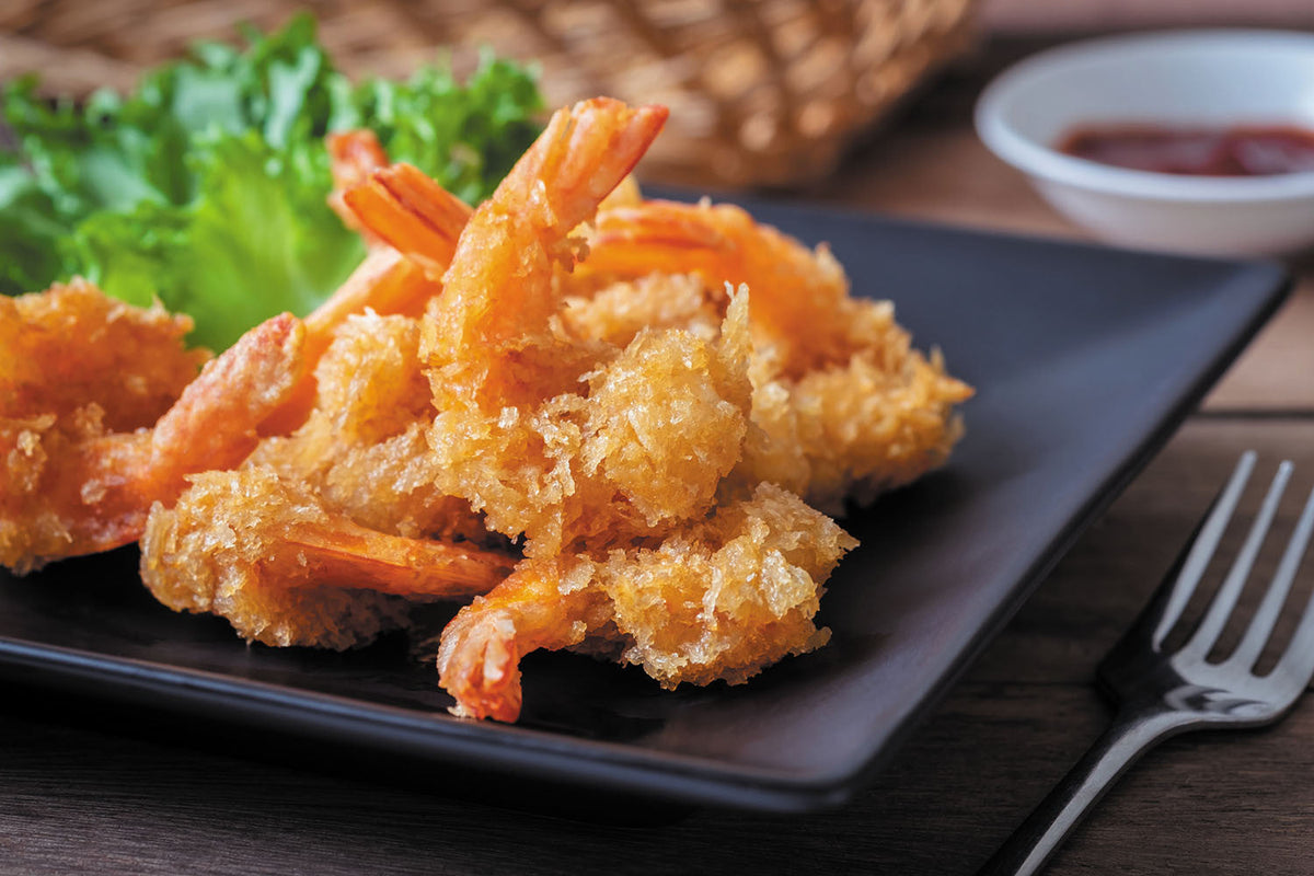Golden breaded shrimp with dip and lettuce garnish on a dark plate