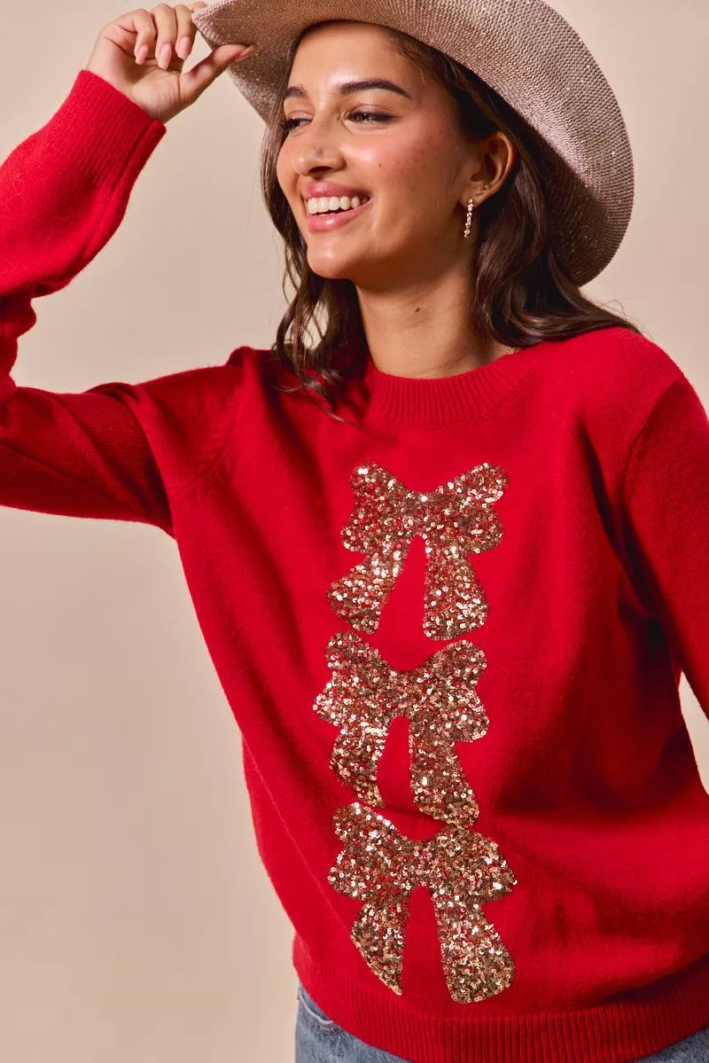 Red sweater featuring gold glitter sequin bow ribbon embellishment on front panel