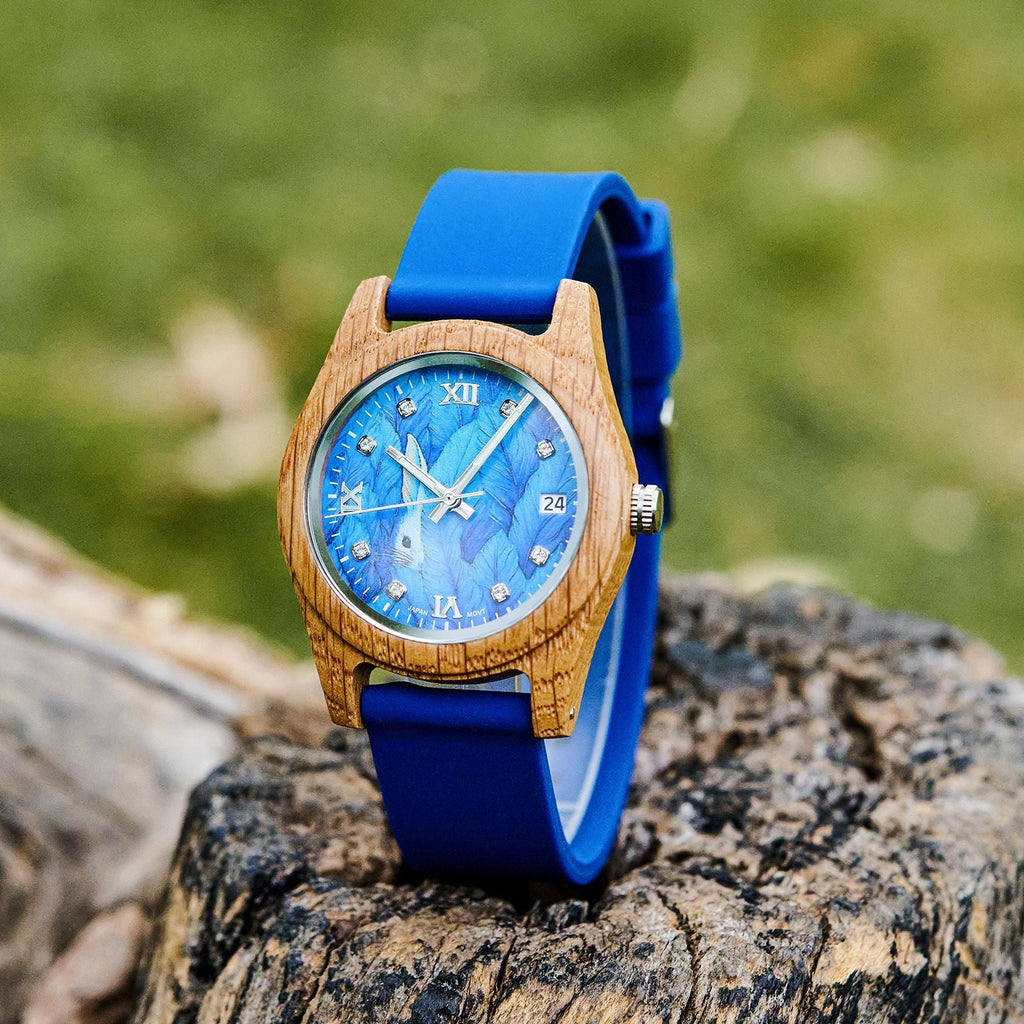 Blue wood wristwatch with roman numeral dial, white hands, and blue silicone strap.