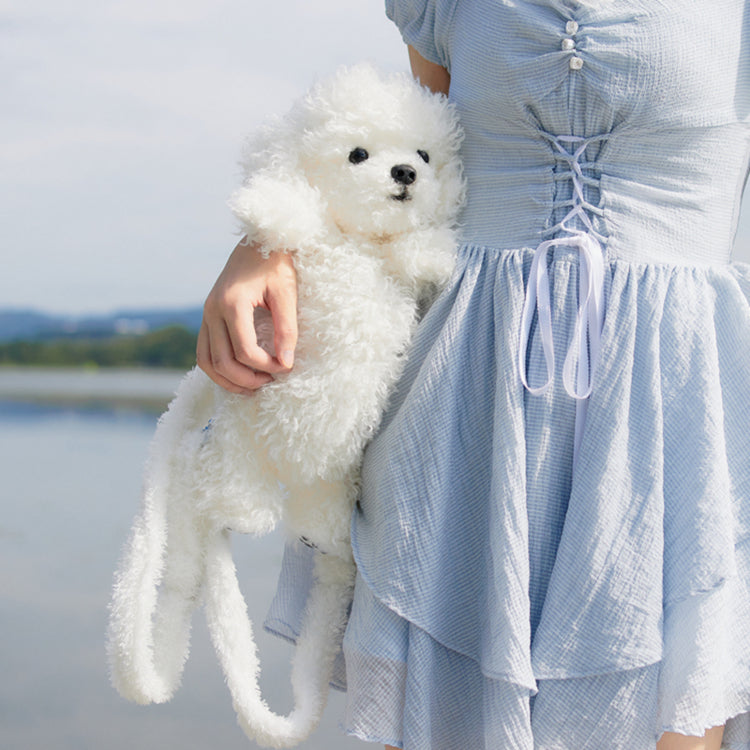 White plush puppy backpack with small paws and soft texture, held close to body