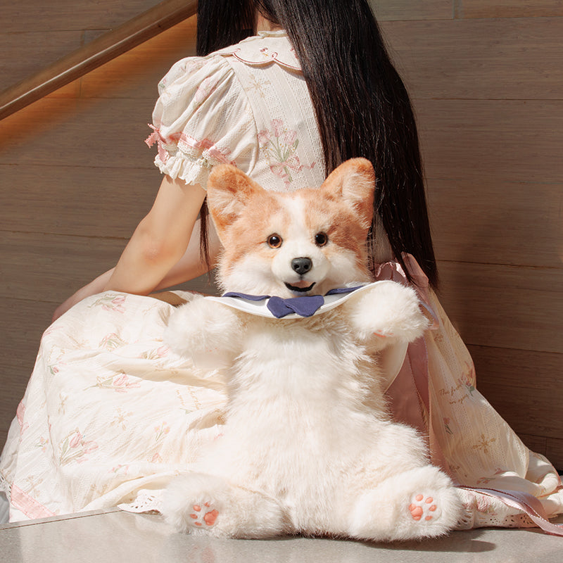 Corgi plush backpack on lap, showing plush corgi face and navy bow collar