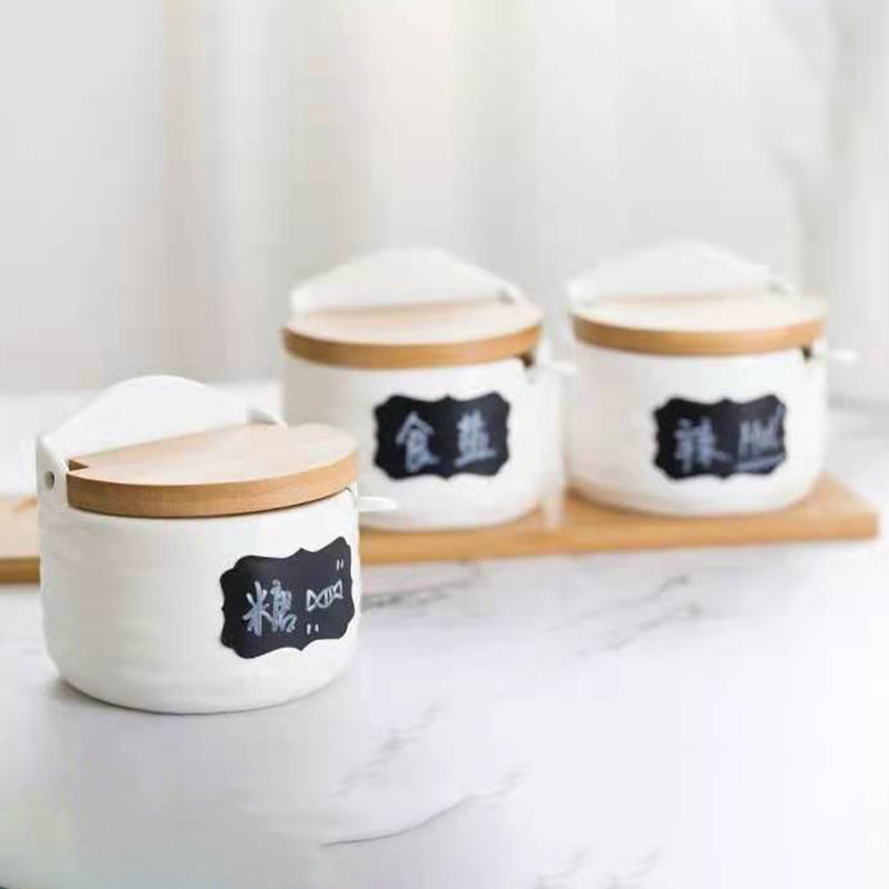 Three white ceramic seasoning cans with wooden flip-top lids and dark blue label