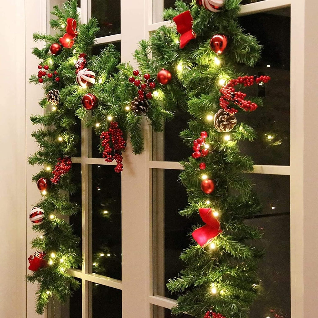 LED Christmas garland with pine tips, red berries, bows, and warm white light strands