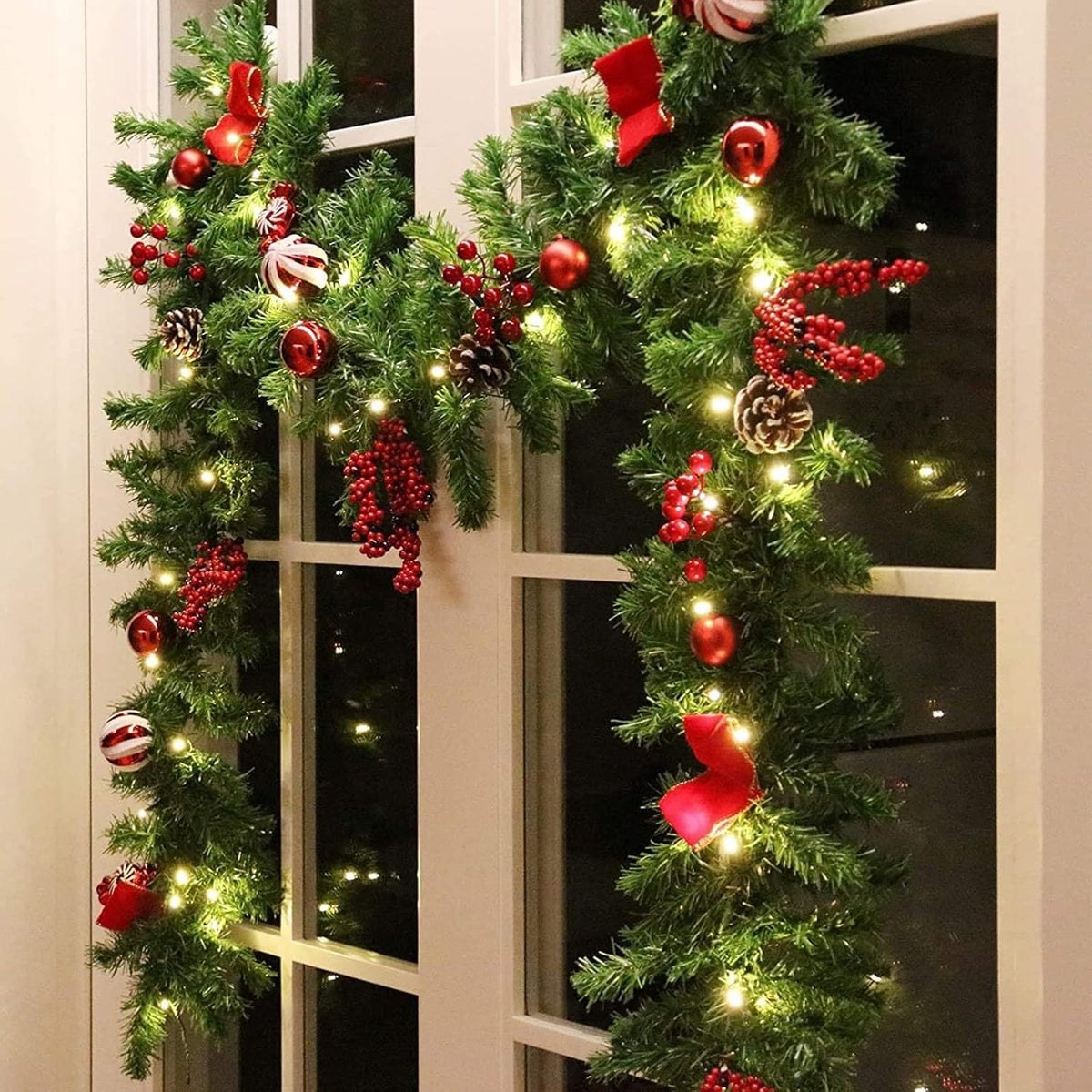 LED Christmas garland with pine tips, red berries, bows, and warm white light strands