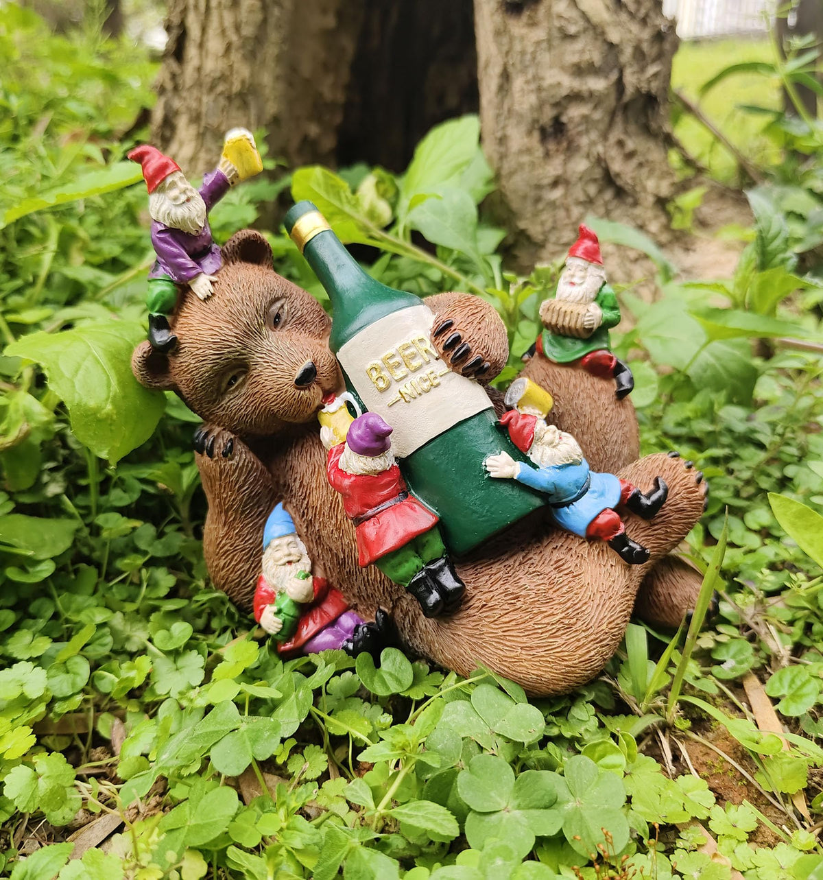 Garden bear yard statue holding a green beer bottle with gnome figurines climbing