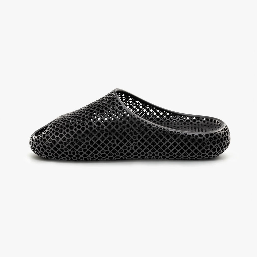 Black 3D-printed mesh slip-on slipper with oval toe cutout detail.