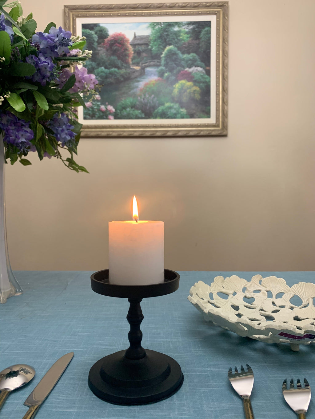 Matte black pillar candle holder with lit white pillar candle