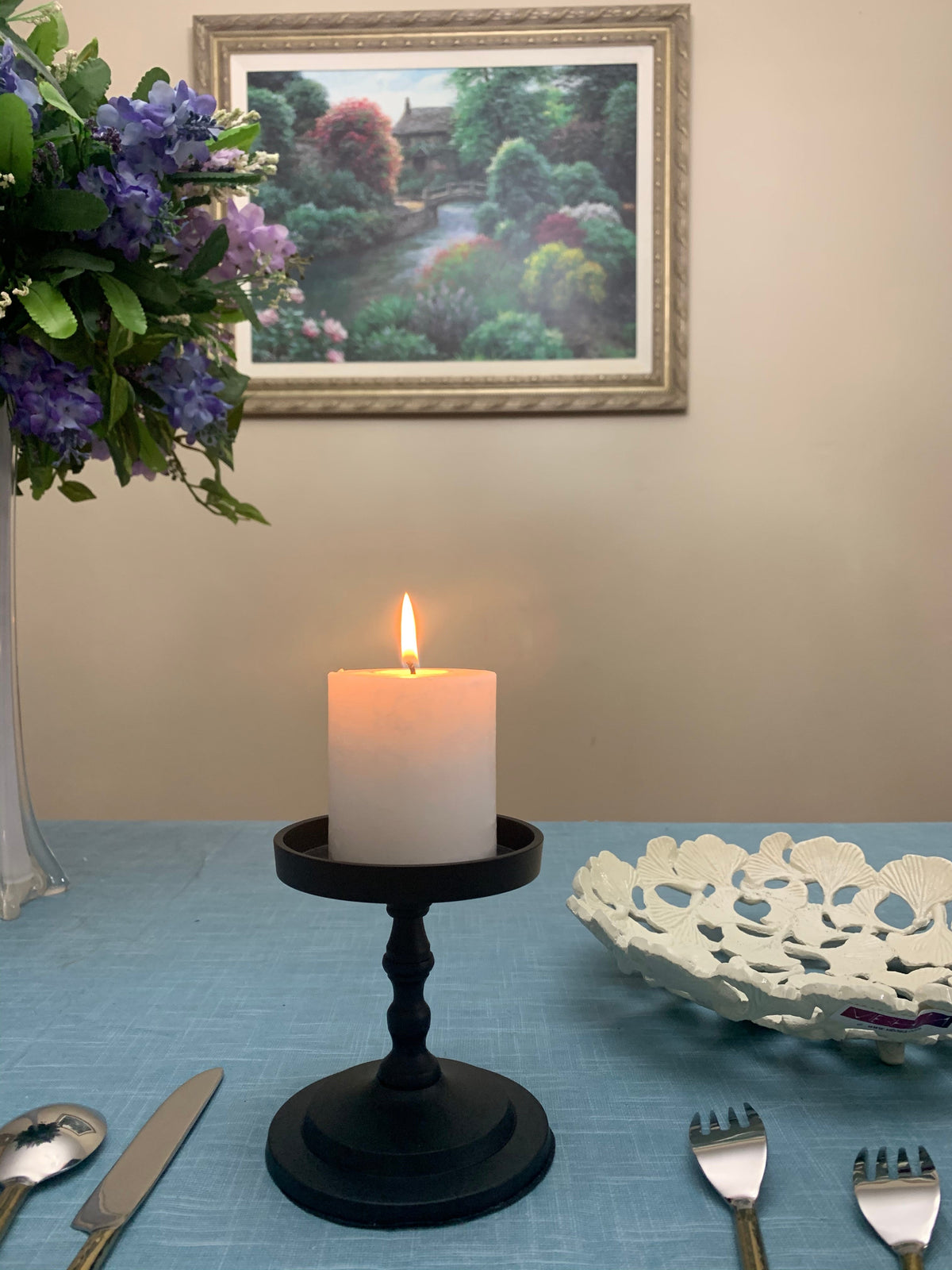 Matte black pillar candle holder with lit white pillar candle