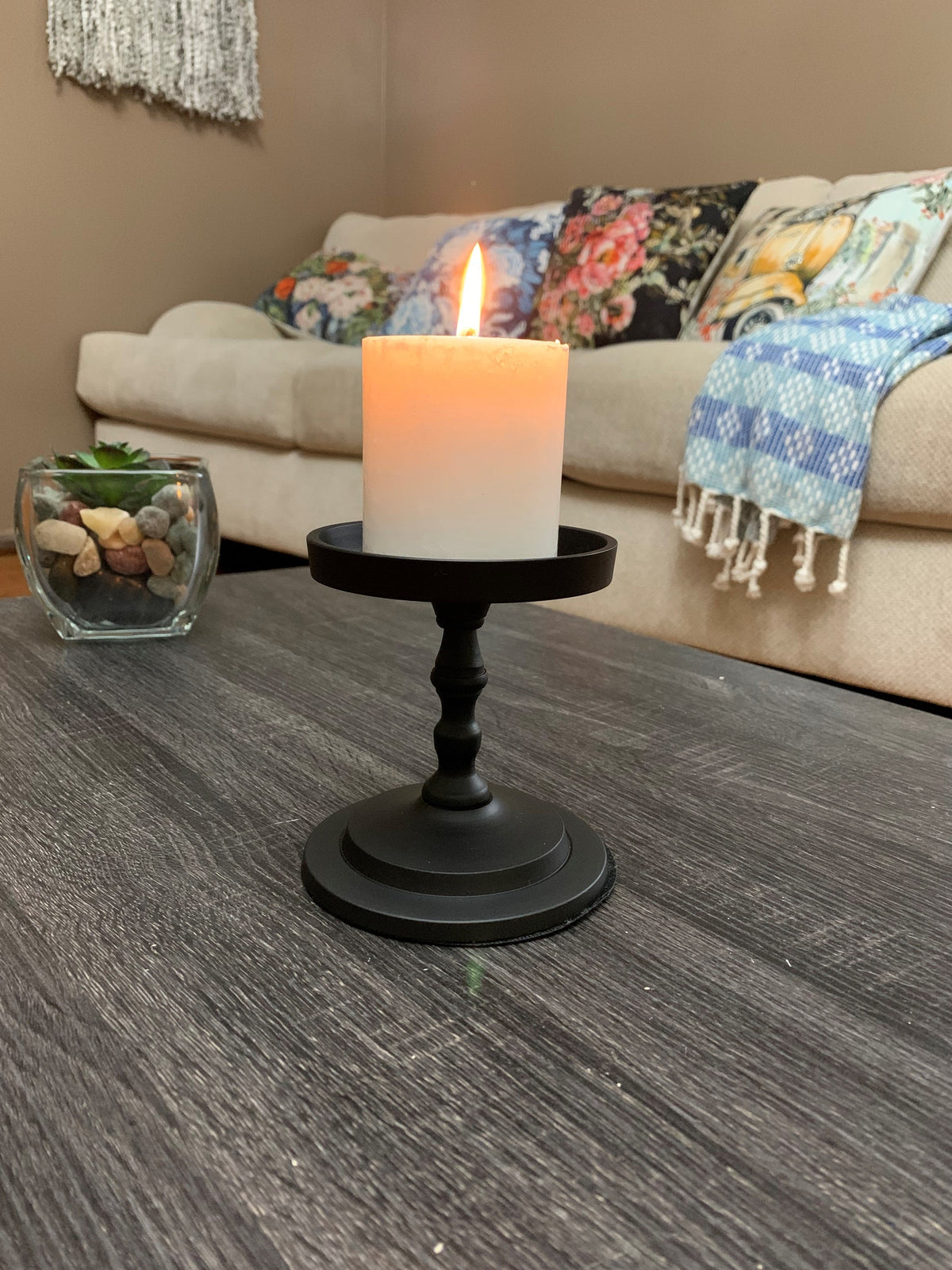 Matte black pillar candle holder with lit white pillar candle