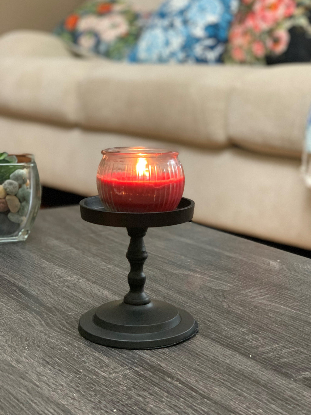 Matte black pillar candle holder with lit red pillar candle