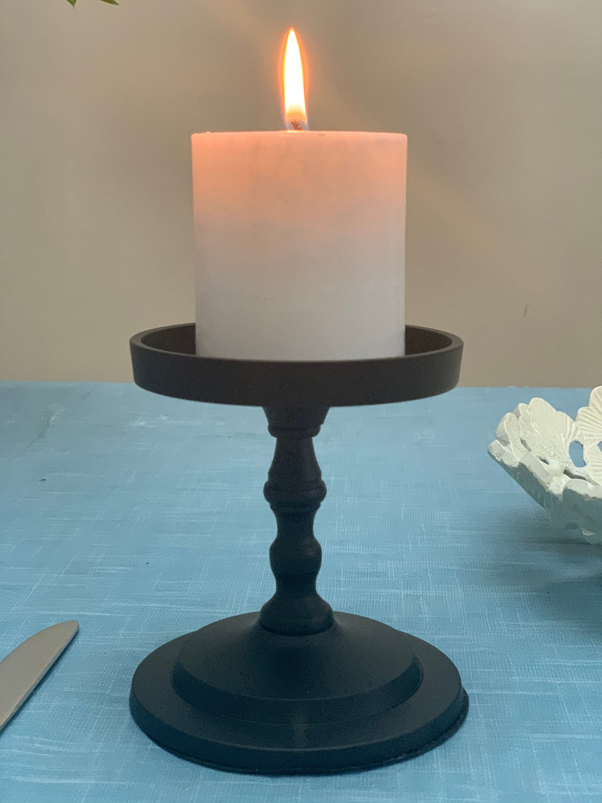 Matte black pillar candle holder with tall lit white pillar candle