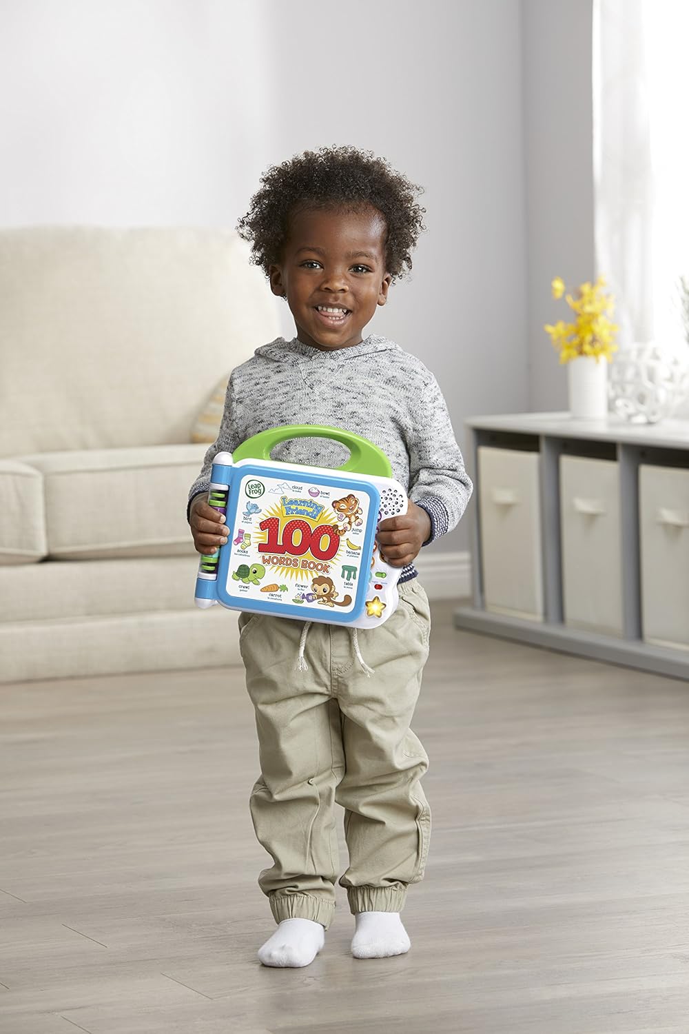 Child holding a green 100 words learning book toy