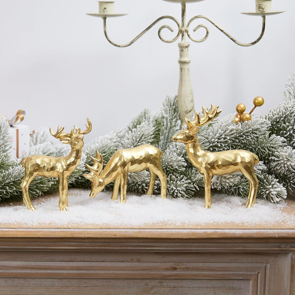 Gold resin reindeer figurines on snowy tabletop, three-piece holiday display