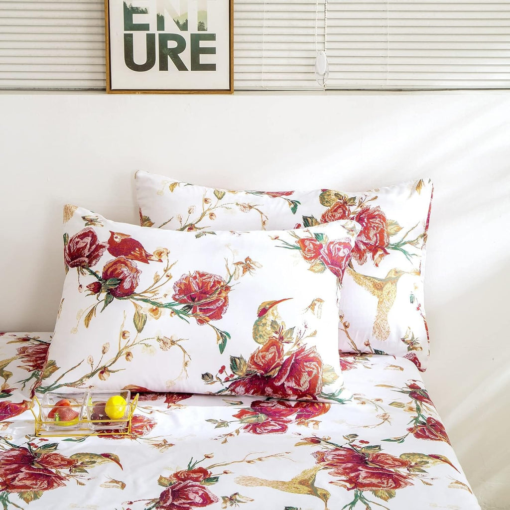 Floral hummingbird pillowcase on bed in white with burgundy roses and gold hummingbird detail.