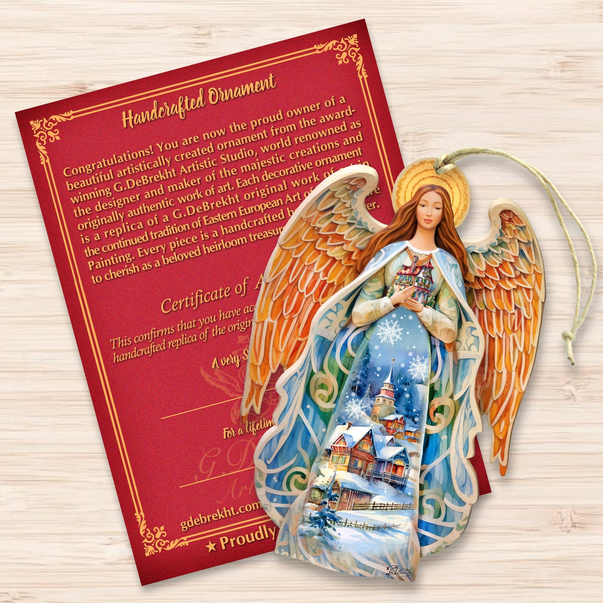 Wooden angel ornament with hanging loop beside certificate card and decorative nativity image