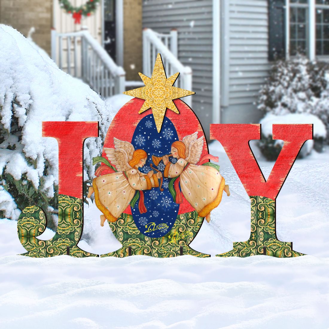 Outdoor “JOY” nativity yard decor with angels and yellow star, red letters on snow.