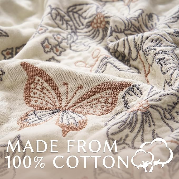 Close-up of taupe-and-white cotton blanket with embroidered floral and butterfly pattern