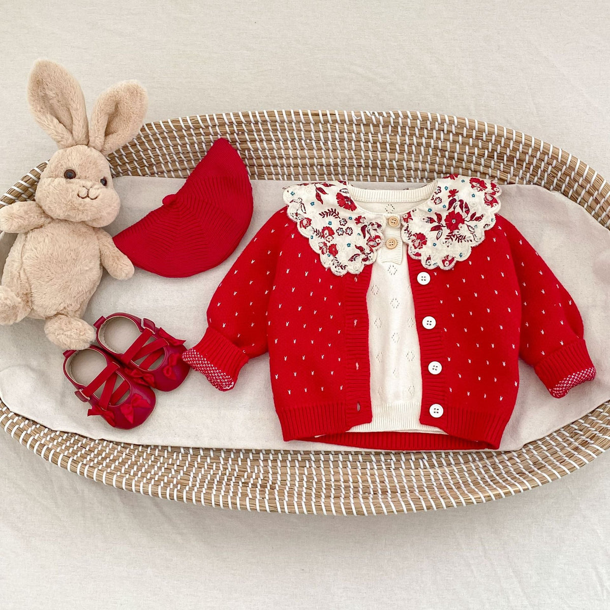 Red dot-knit cardigan with button front and ruffled cuffs over a white outfit