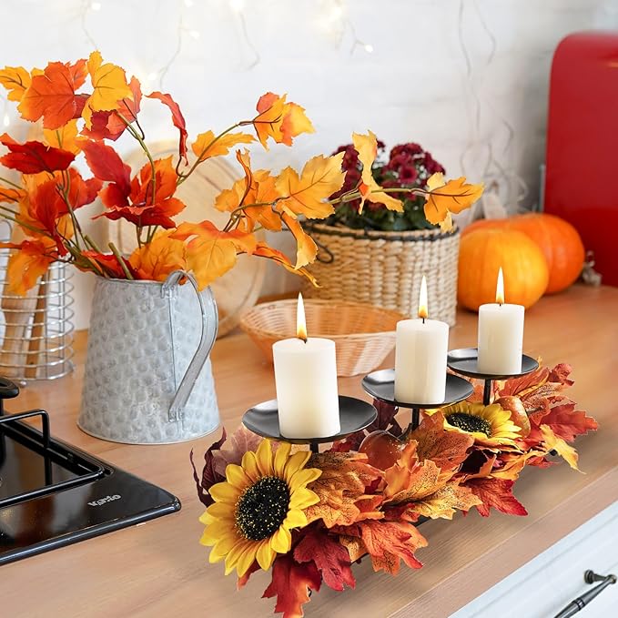 Black metal three-candle holder tray with three white pillar candles and autumn leaves