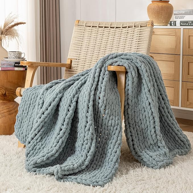 Chunky cable-knit chenille throw blanket in blue on a chair and floor