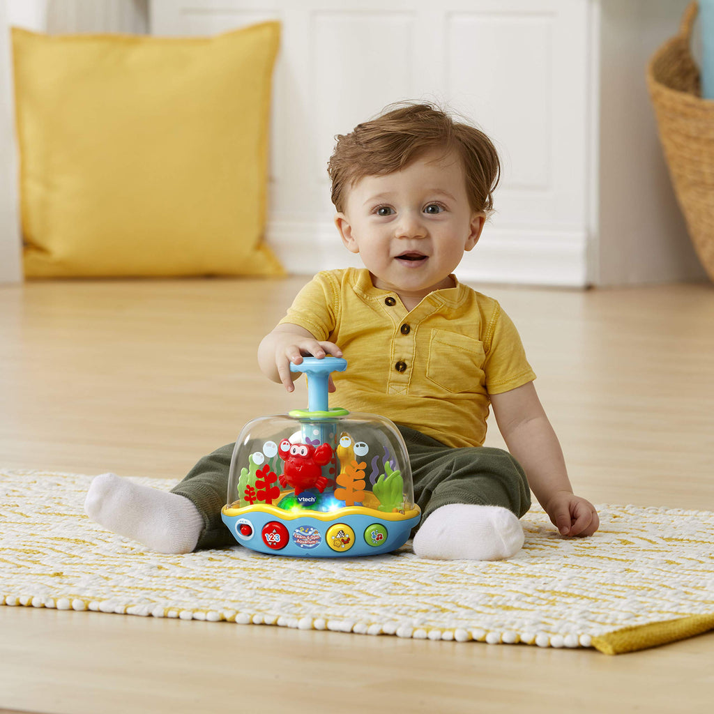 Baby playing with spinning ocean adventure aquarium on living-room carpet