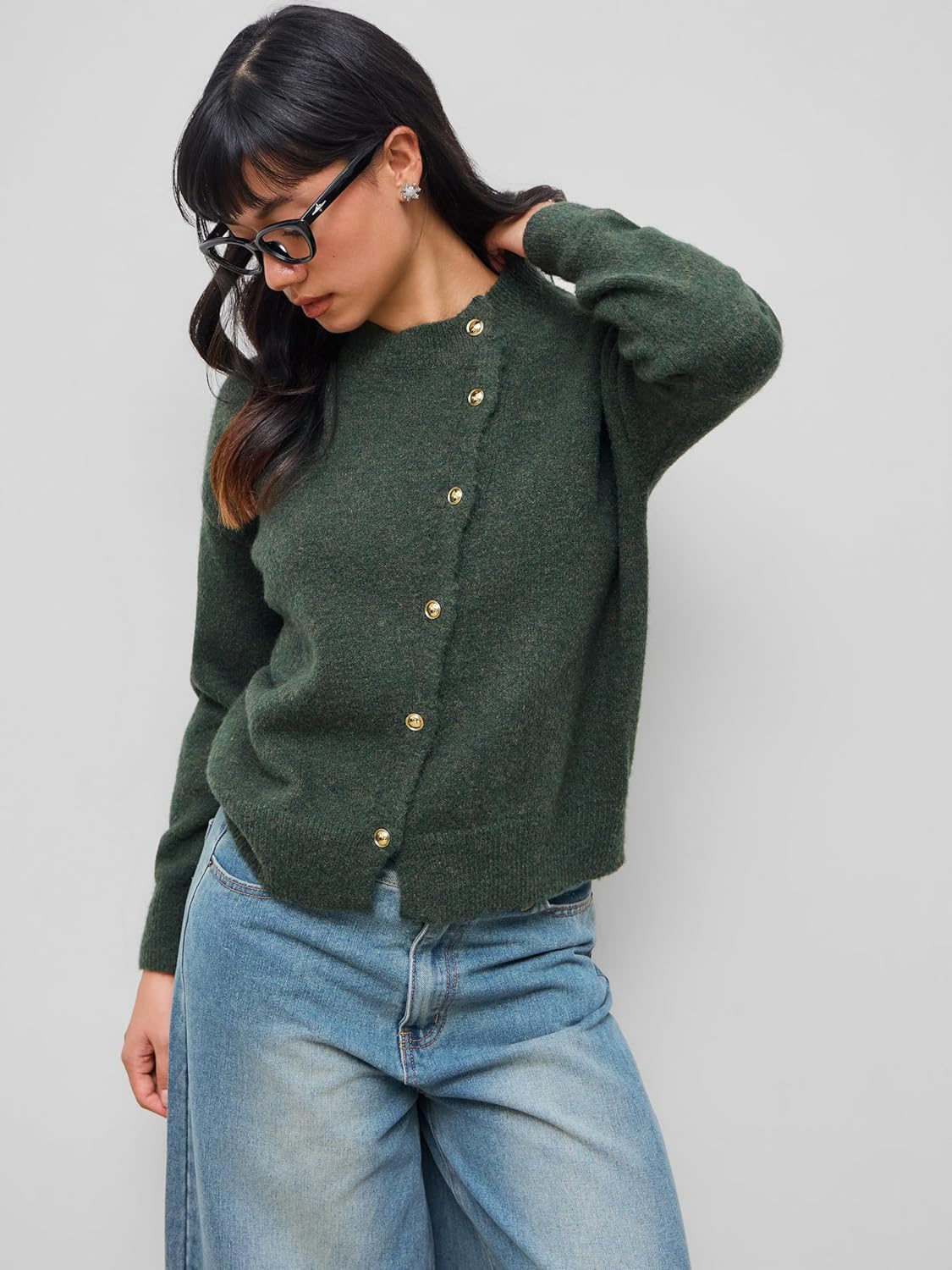 Dark green knit cardigan on model, crew neck and long sleeves with gold snap buttons