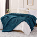 Chunky cable knit chenille throw blanket, dark teal blue, draped over bed