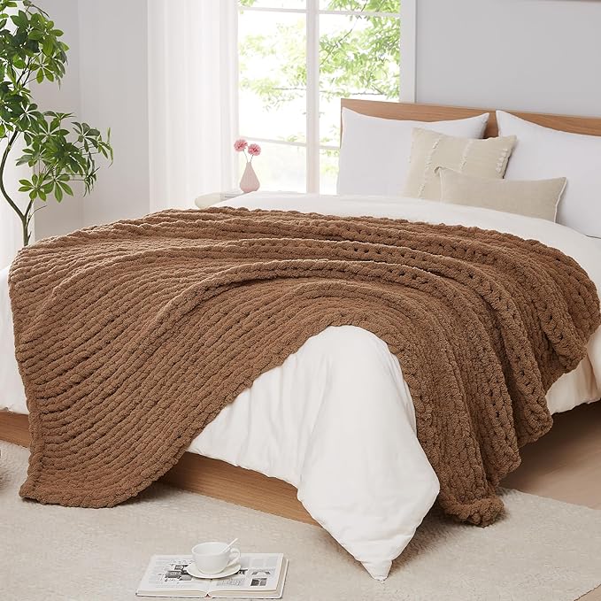 Brown chunky cable-knit throw blanket, folded over a bed